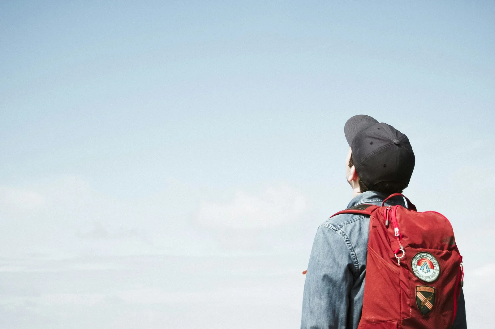 A student with a backpack gazing up at a clear blue sky at the start of their study abroad journey