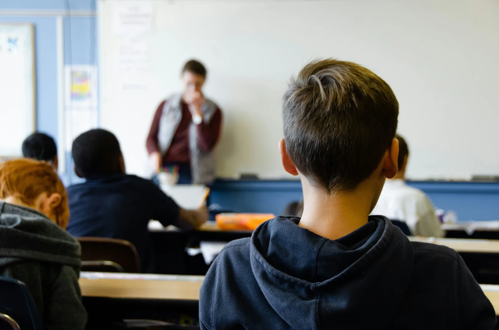 A focused student listening to a lecturer during a class in a bright classroom